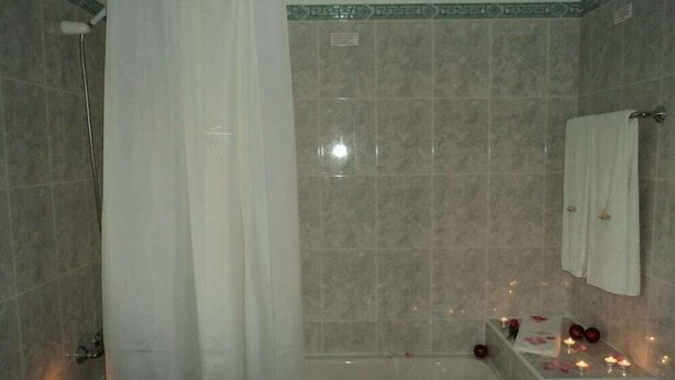Un baño con bañera, cortina de ducha y toallero.