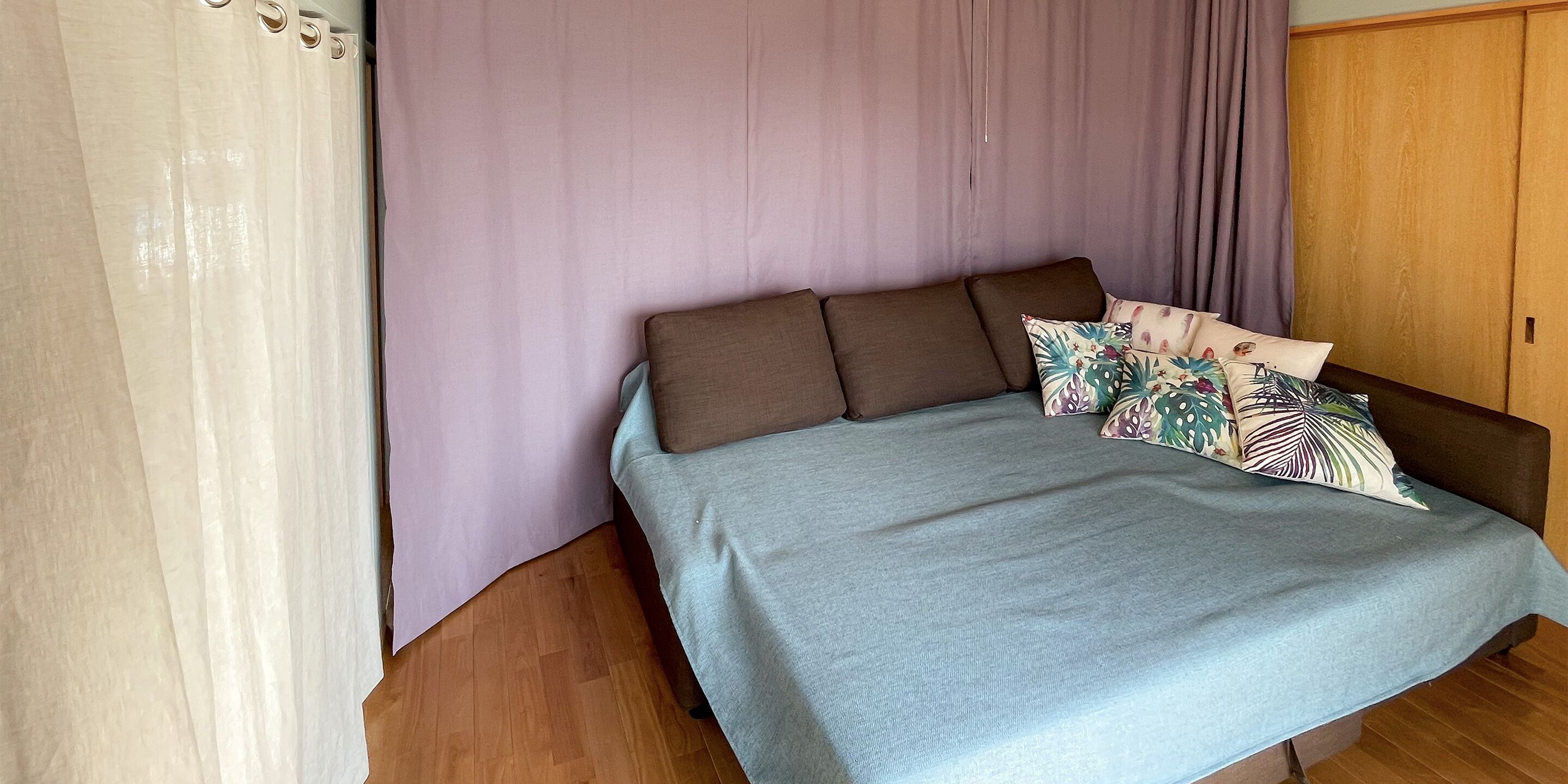 A bedroom with a bed, curtains, and a wardrobe.