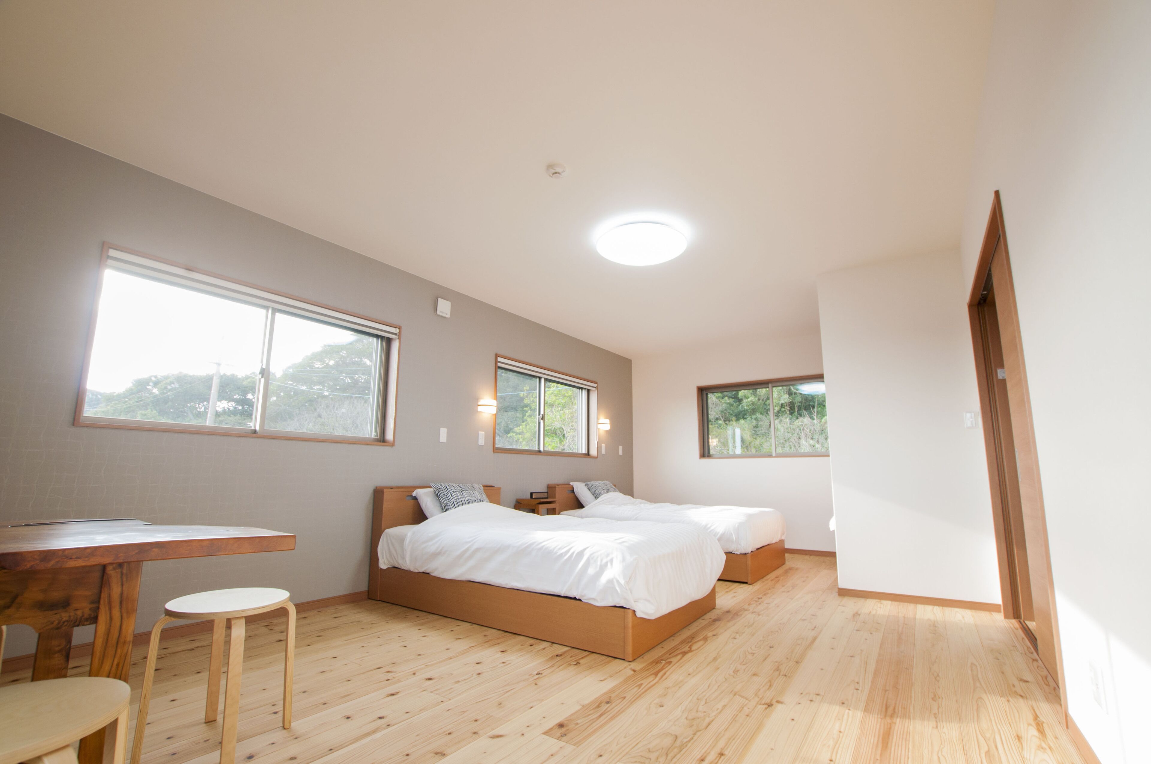 A bedroom with two beds, a wooden desk, and a window.