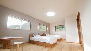 A bedroom with two beds, a wooden desk, and a window.