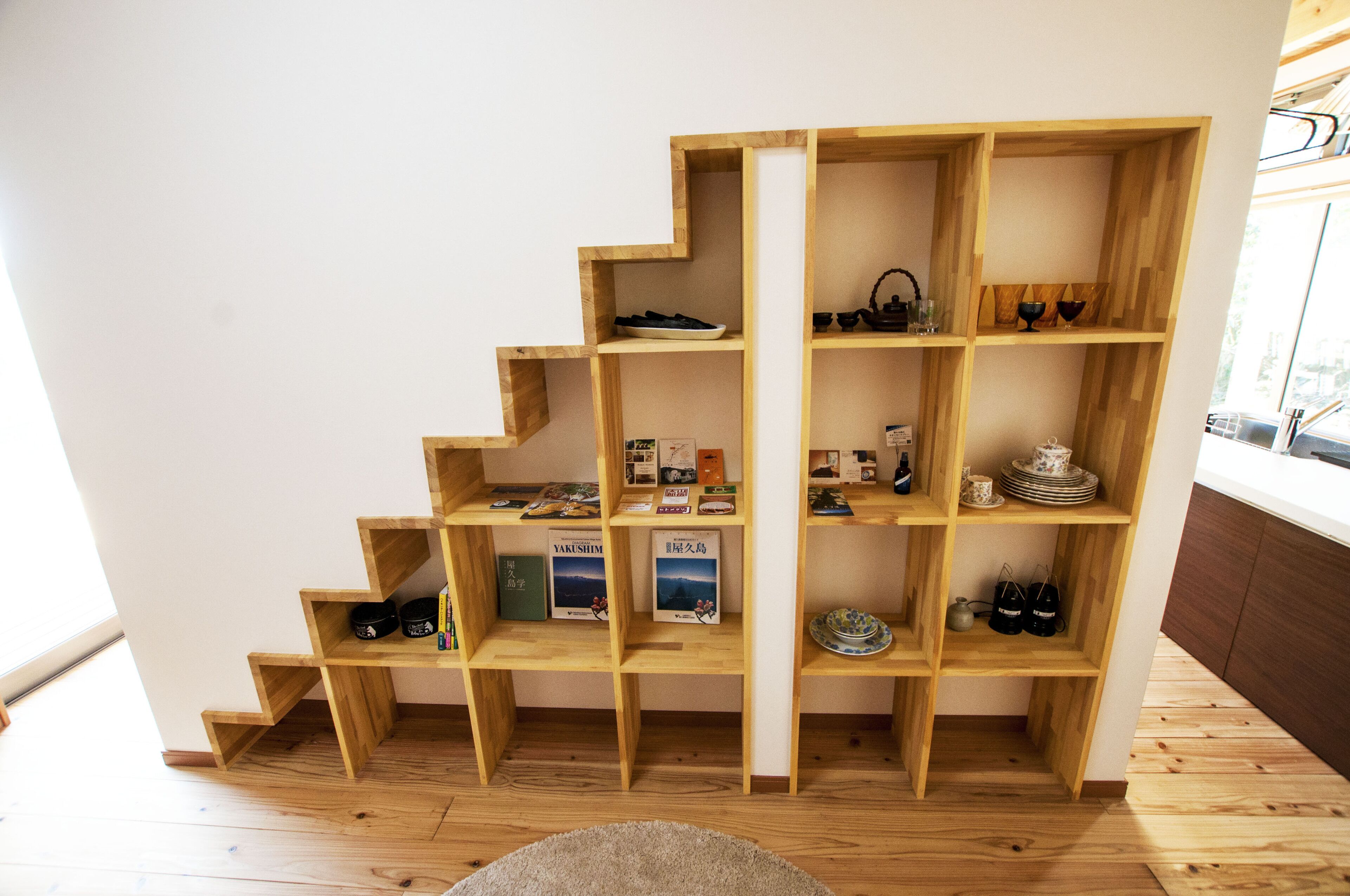 A wooden bookshelf with multiple shelves containing books, decorative items, and small objects.