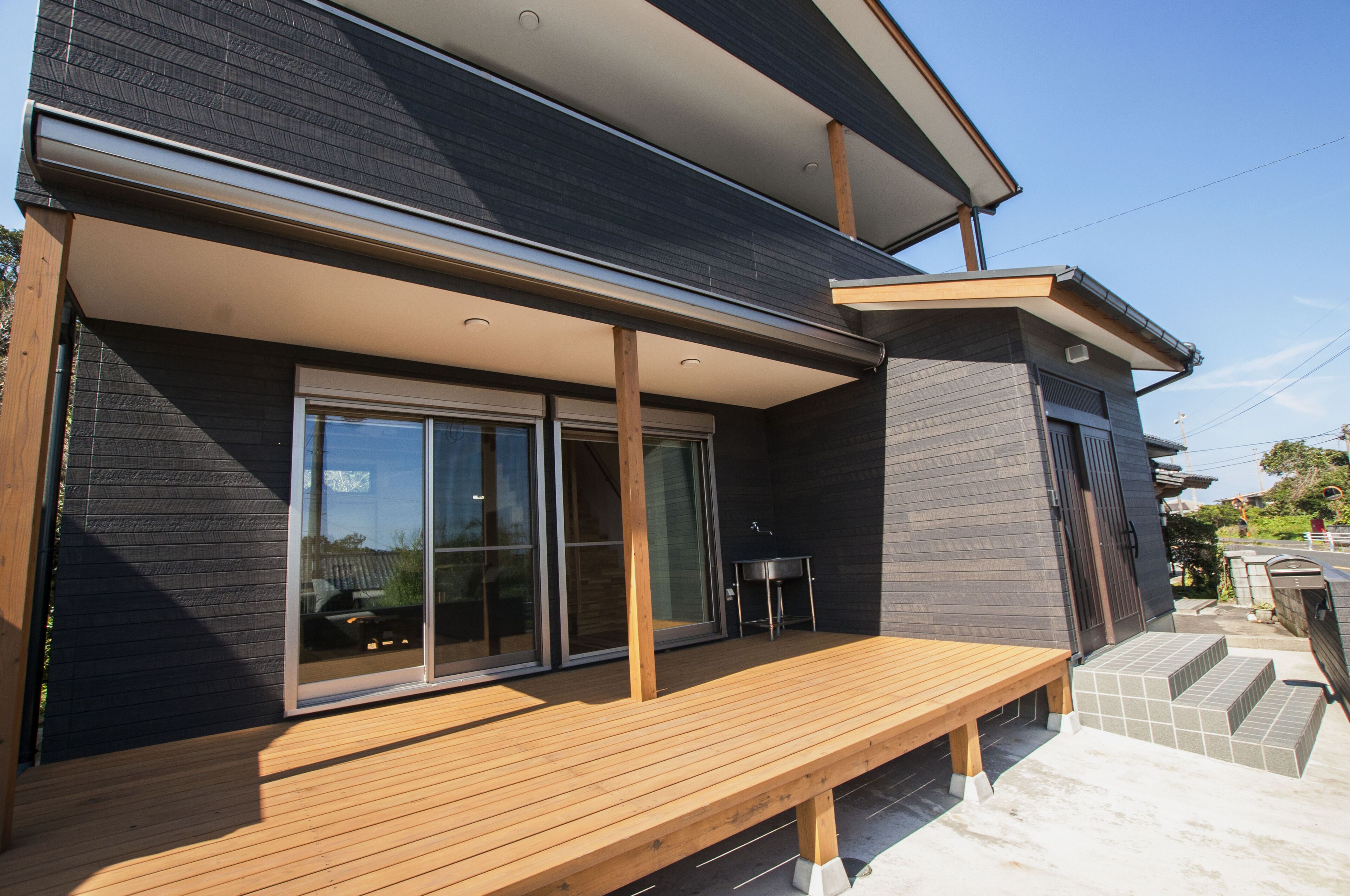 A modern house with a wooden deck, large sliding glass doors, and a small outdoor table.