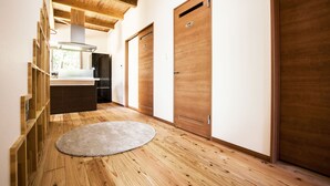 A hallway with wooden flooring, a round rug, and wooden doors.