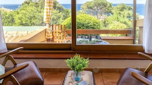 Eine Terrasse mit Meerblick, Holzmöbel und einem Tisch mit einem Buch und einer Pflanze.