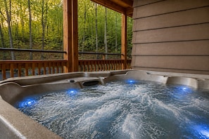 A hot tub with a wooden deck and a forest backdrop. - Top Resort with 3 Pools/Pickleball/Hot Tub/Games (Gatlinburg)