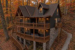 A multi-story cabin with a stone foundation, wooden balconies, and a steeply pitched roof. - Top Resort with 3 Pools/Pickleball/Hot Tub/Games (Gatlinburg)