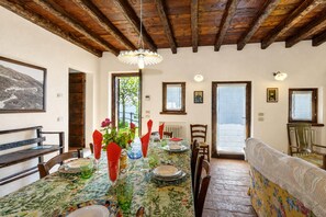 Uma sala de jantar com uma mesa posta para quatro pessoas, cadeiras de madeira, um banco e um sofá.