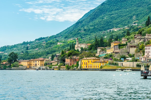 A coastal town with buildings along the waterfront, a hill in the background, and boats on the water. - Villa Formaga | Stunning View&Garden and, Gargnano, Italy (Gargnano)