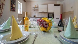 Una mesa de comedor dispuesta con platos, vasos y un frutero.