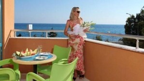 A balcony with a table set for two, overlooking the sea. - Merlin Beach Park Hotel (Alanya)