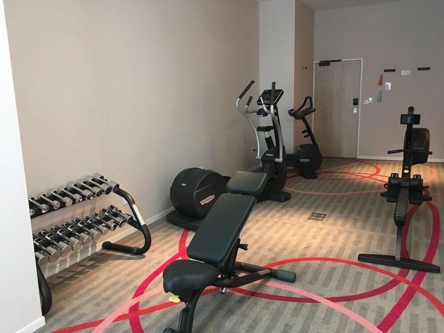 Uma academia com equipamentos de ginástica, incluindo halteres, um banco e aparelhos cardiovasculares.