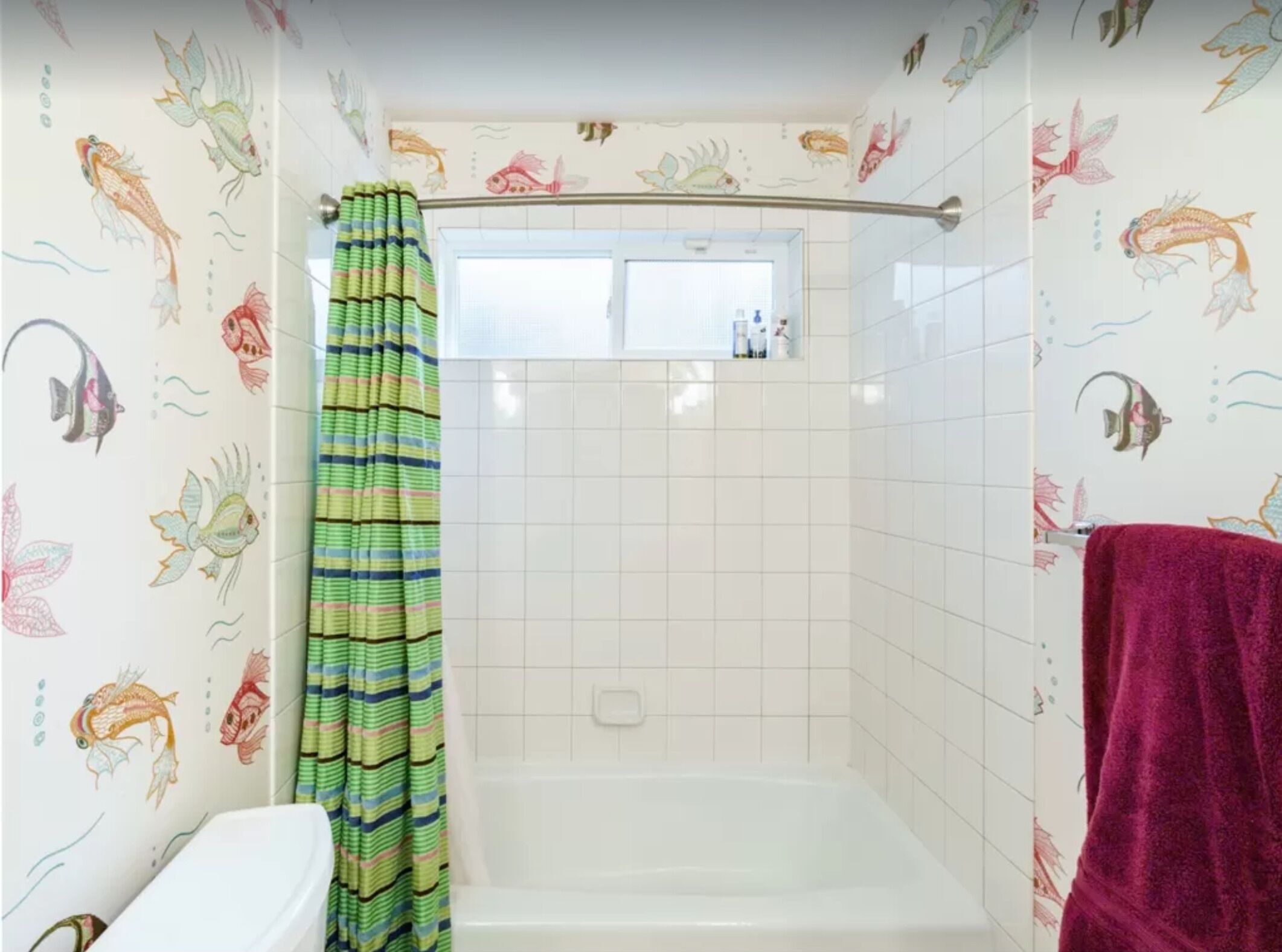 A bathroom with a shower, tiled walls, and a window.
