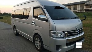 A silver van parked on a road with a building in the background. - Dmk Don Mueang Airport Guest House Meet-greet Service (Bangkok)