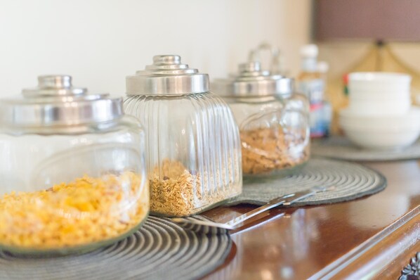 A kitchen counter with glass jars containing grains and spices, a metal tray, and a white bowl in the background.