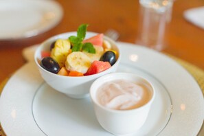 A white plate with a bowl of fruit salad and a small bowl of yogurt. - Lovely Guesthouse in Pretoria Welcoming you on a Spacious Room With Breakfast (Pretoria)