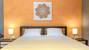 Ett hotellrum med en säng, två sänglampor och en dekorativ väggdekoration.