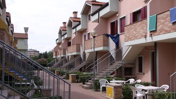 Un immeuble résidentiel doté de nombreux balcons, d’un escalier central et d’espaces aménagés pour se détendre à l’extérieur.
