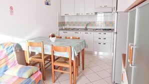 Une cuisine compacte avec des meubles blancs, un pare-feu en carreaux et un coin repas comprenant une table et des chaises.