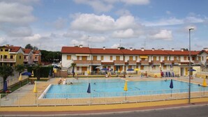 Une piscine entourée d’une rangée de bâtiments aux couleurs vives, dotés de balcons.