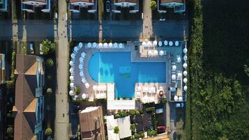An aerial view of a residential area with a swimming pool surrounded by lounge chairs and umbrellas.