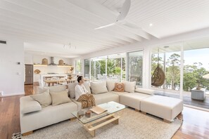 A spacious living area with a large sectional sofa, a glass coffee table, and a view of the outdoors. - Paradise by the lake (Green Point)