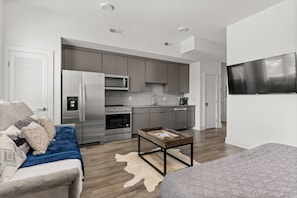 A modern apartment with a kitchenette, a dining area, and a living room with a sofa and coffee table.