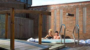 A wooden deck with a hot tub and metal ladders.