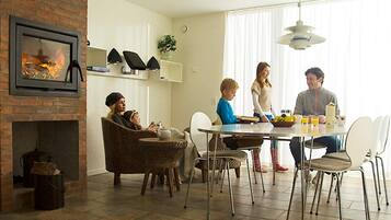 A dining area with a brick fireplace, modern chairs, and a dining table.