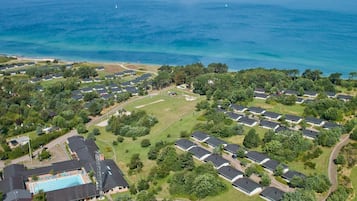 Vista aérea de una zona residencial costera con varias casas, una piscina y una vista despejada del océano.