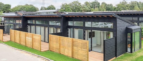 A row of modern, black-roofed cabins with large windows and wooden fences.