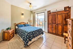 A bedroom with a bed, wooden wardrobe, and a balcony with a chair.