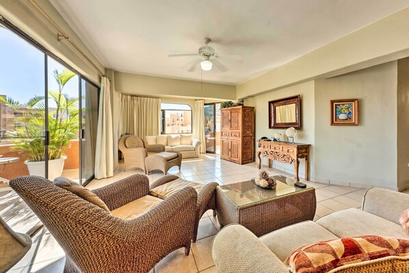 A spacious living area with a large window, a ceiling fan, and a view of buildings outside.