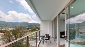 A balcony with a table and chairs, offering a view of a town and mountains. - Oceana C51 (Kamala)