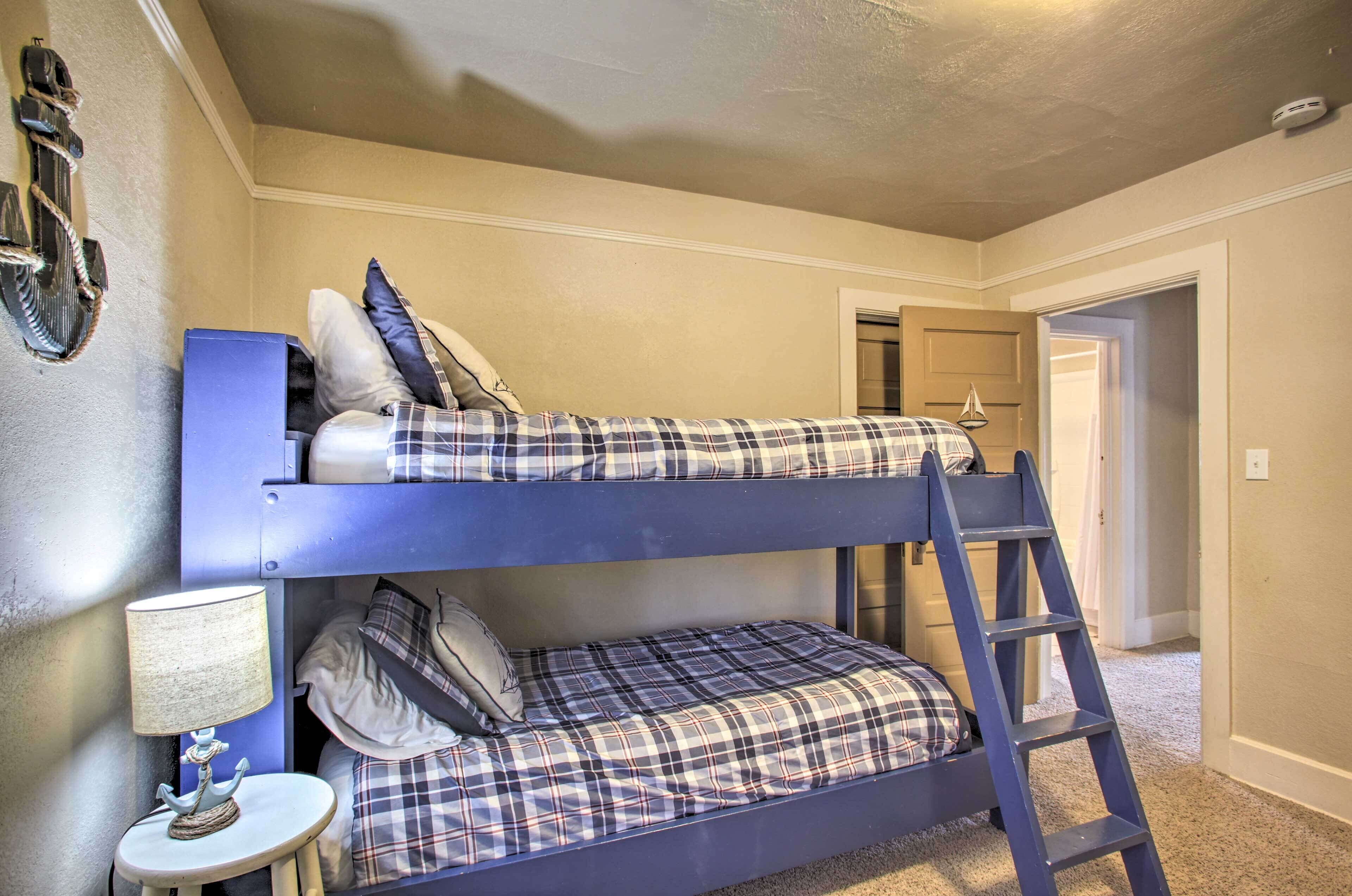 Una cama litera con escalera, una mesita con lámpara y un adorno en la pared.