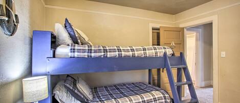 Una cama litera con escalera, una mesita con lámpara y un adorno en la pared.