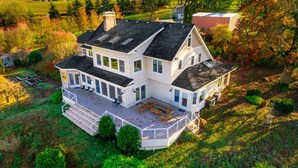 Une grande maison à deux étages, dotée d’un patio couvert et de nombreuses fenêtres.