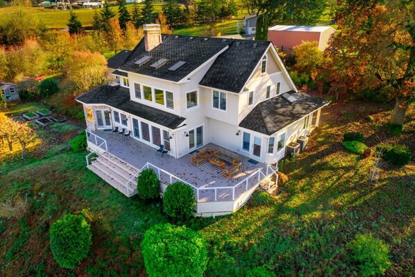 A large, two-story house with a covered patio and multiple windows. - Breathtaking Valley Views, Pet Friendly, Huge Deck, Fire-Pit, Air Hockey, Ping Pong, Near Vineyards (Newberg)