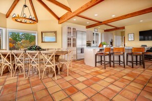 A spacious kitchen with white cabinets, a central island, and a dining area with wooden chairs. - Breathtaking Valley Views, Pet Friendly, Huge Deck, Fire-Pit, Air Hockey, Ping Pong, Near Vineyards (Newberg)