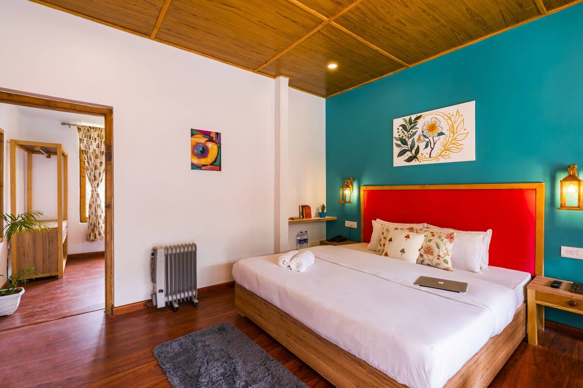 A bedroom with a wooden bed, a red headboard, a blue accent wall, and a potted plant.