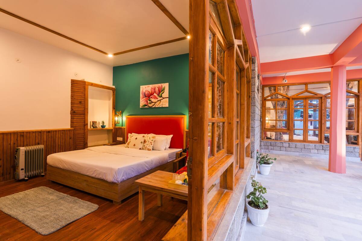 A bedroom with a wooden bed, a nightstand, a radiator, and a view of the outside.