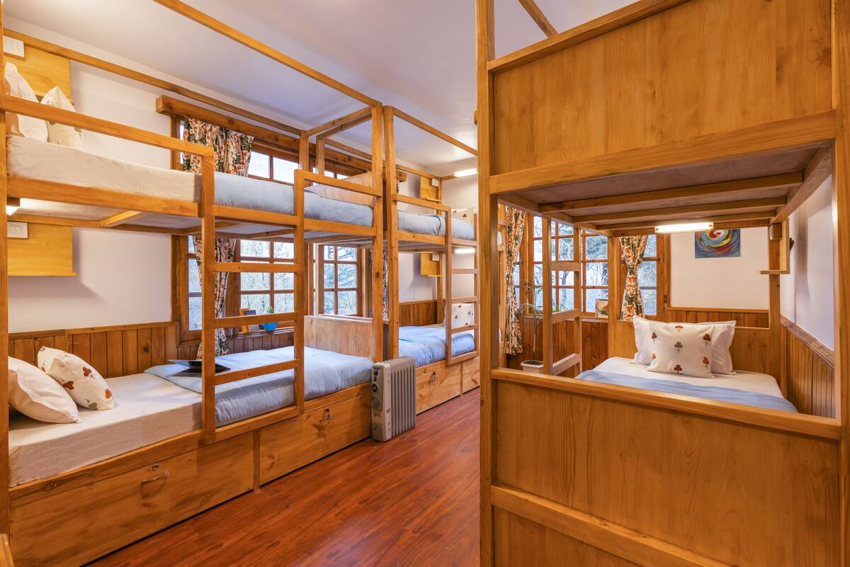 A room with bunk beds, wooden walls, and a radiator.