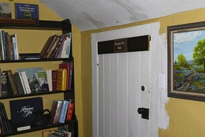 A room with a bookshelf, a white door, and a painting on the wall.