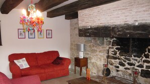 A cozy living room with a red sofa, a wooden coffee table, and a stone fireplace. - Luxury gite for adult couples, peaceful, open views, large swimming pool (Boisse)