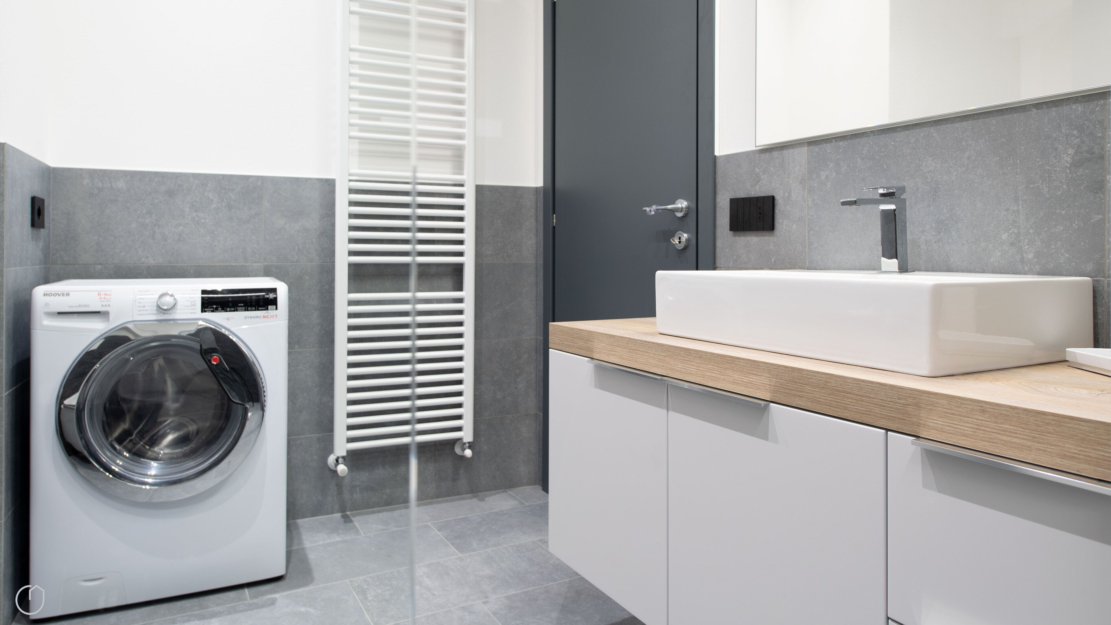 Een moderne badkamer met een ingebouwde wasmachine, een wastafel en een spiegel.