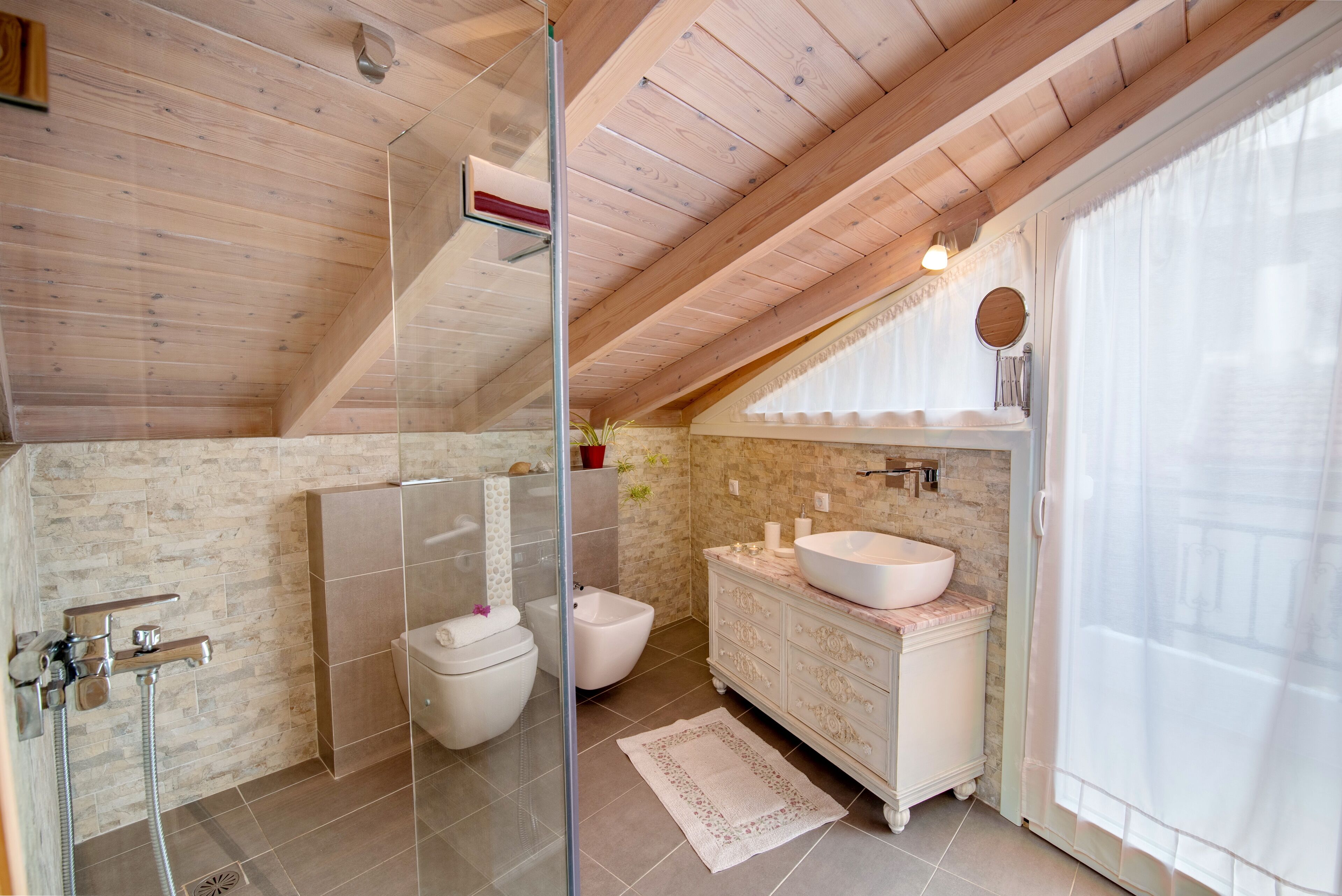 Une salle de bain moderne avec une douche à l’italienne en verre, un lavabo blanc et un meuble-lavabo en marbre.