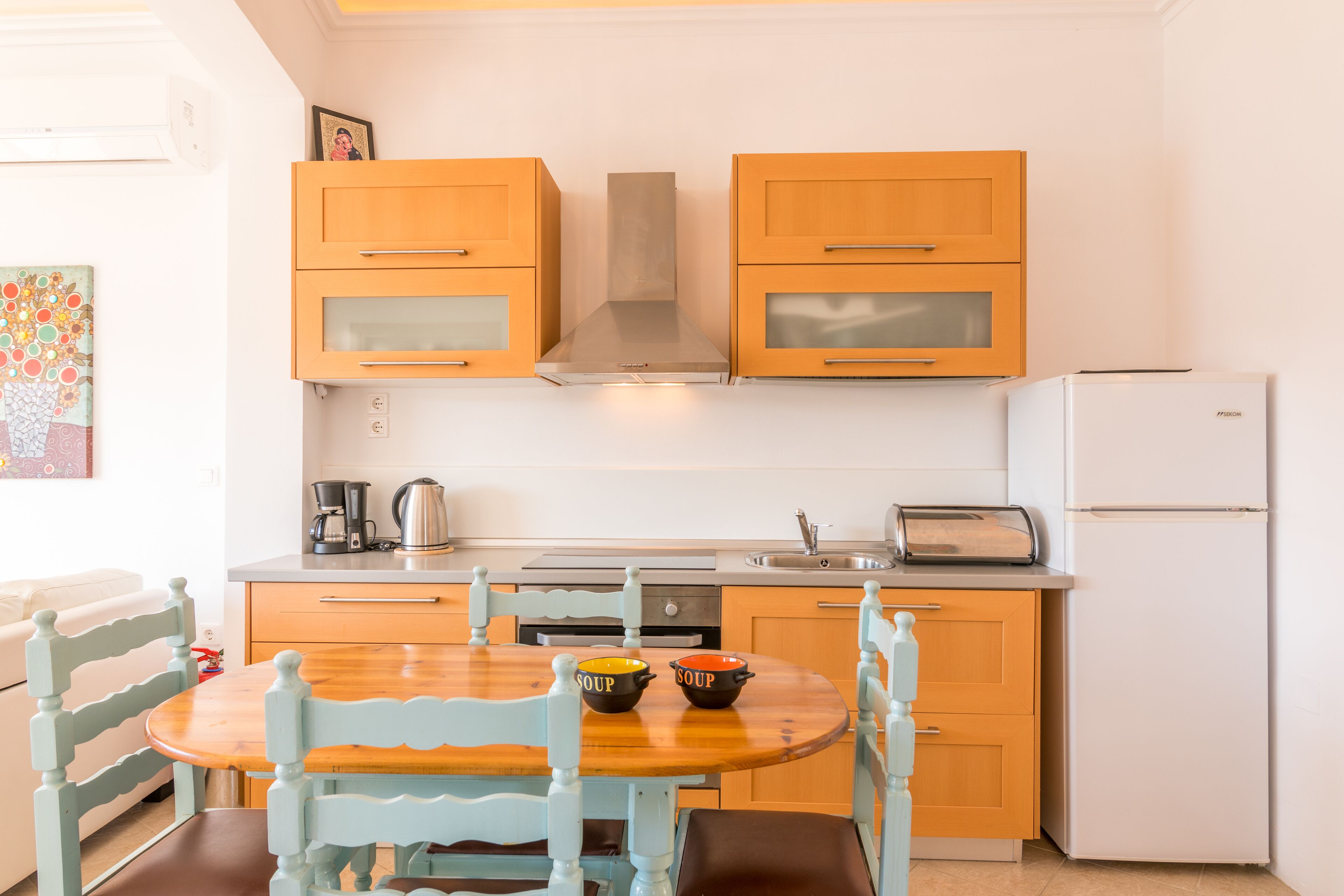 Una cucina con mobili in legno, un fornello, un lavello e un tavolo da pranzo con sedie.