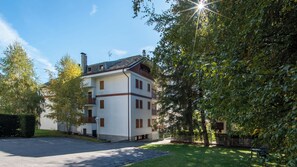 Un edificio a più piani con facciata bianca, balconi e un'area di parcheggio antistante.