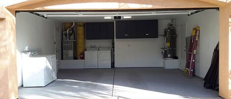 Un garage équipé d’une machine à laver, de placards, d’un chauffe-eau et d’une échelle.