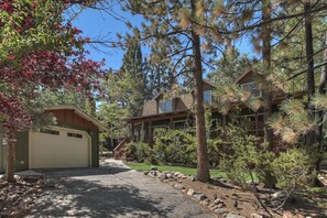 A two-story house with a garage, surrounded by dense pine trees and a well-maintained lawn. - Peace Out by Destination Big Bear : Remarkable Dutch Gambrel Only 2 Blocks from Snow Summit! Foosball! (Big Bear Lake)