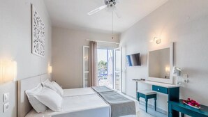 A modern hotel room with a bed, bedside table, TV, and a view of the outdoors. - Oniro Pension (Alonissos)